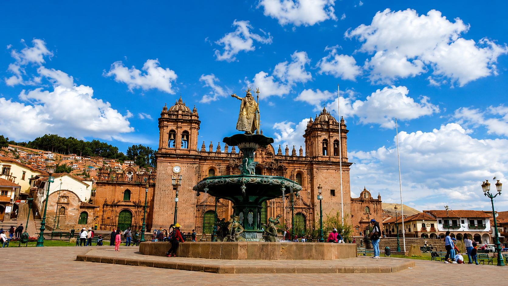 La fuente del Inca está en el centro de la Plaza de Armas del Cusco, frente a la iglesia de la Compañía de Jesús. La gente cruza la plaza bajo un cielo azul.
