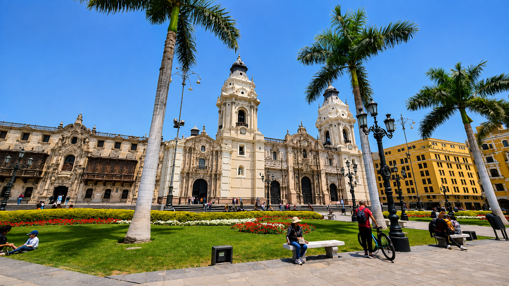 La Catedral de Lima se ve detrás de palmeras altas y un jardín con flores. La gente descansa en las bancas de la Plaza de Armas.