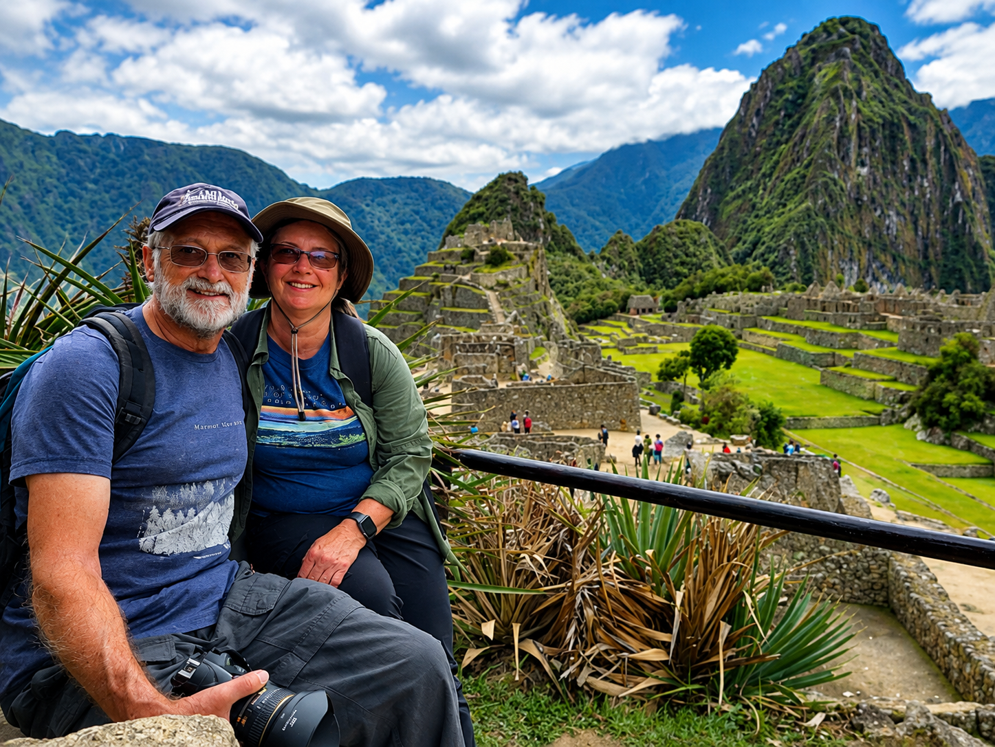 Una pareja sonríe con Machu Picchu detrás, y el Huayna Picchu al fondo. Los andenes verdes bajan entre los muros de la ciudadela.