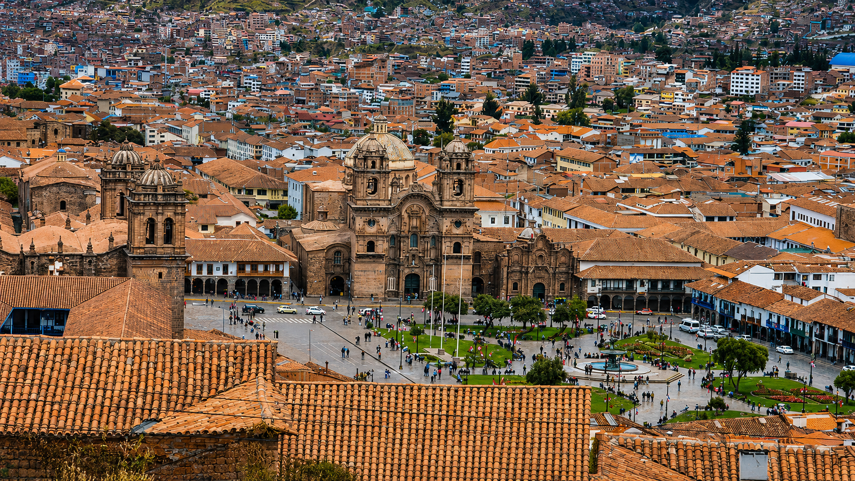 Cusco desde lo alto: un mar de tejas naranjas, la Catedral en el centro de la Plaza de Armas y el verde de los árboles en primer plano.